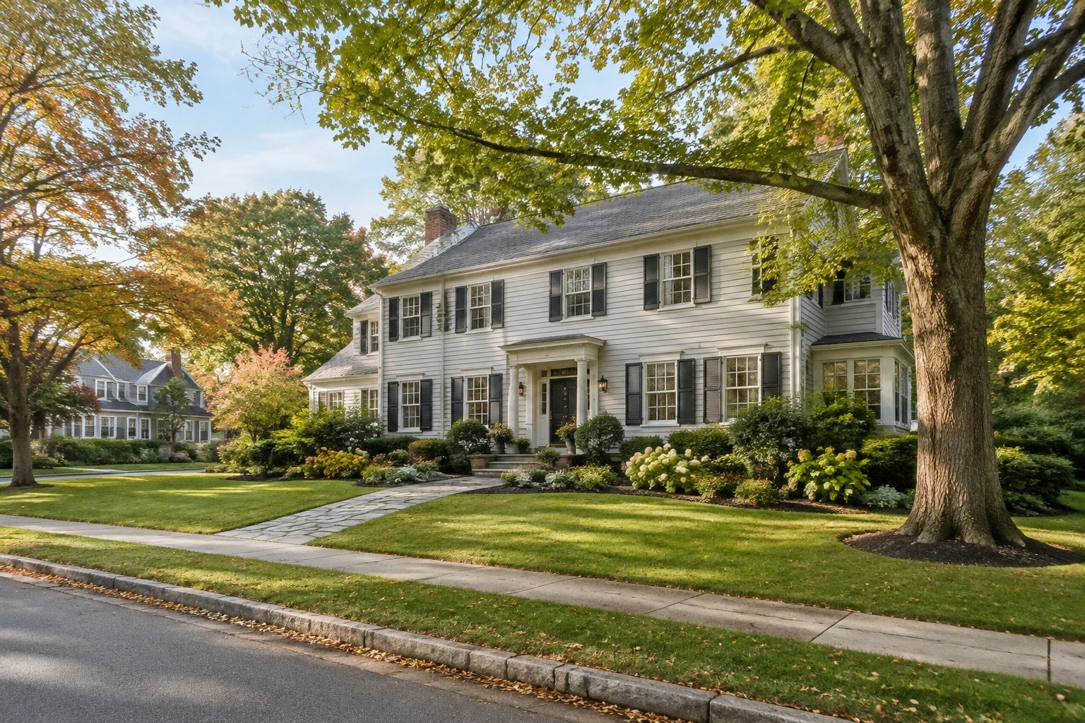 A large Colonial-style home on a landscaped, tree-lined suburban street.