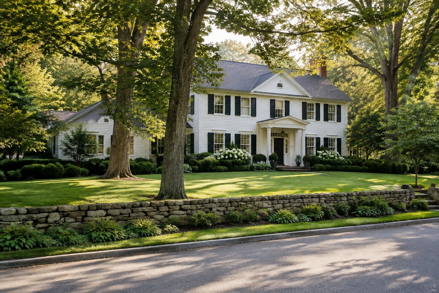 A large New England home sits behind mature trees and a carefully kept lawn.