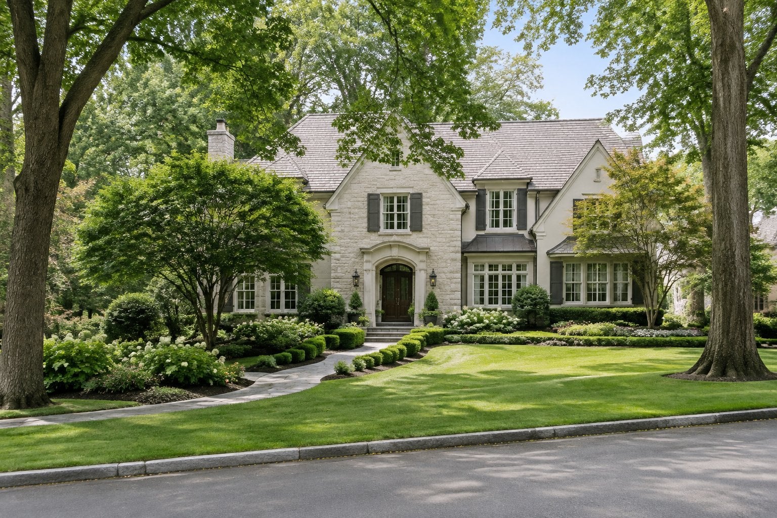 A large home surrounded by landscaped gardens and mature trees on a quiet suburban street.